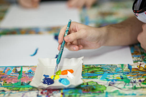 istock Artist's Hand Mixing Acrylic Paints on Palette. 2045397880