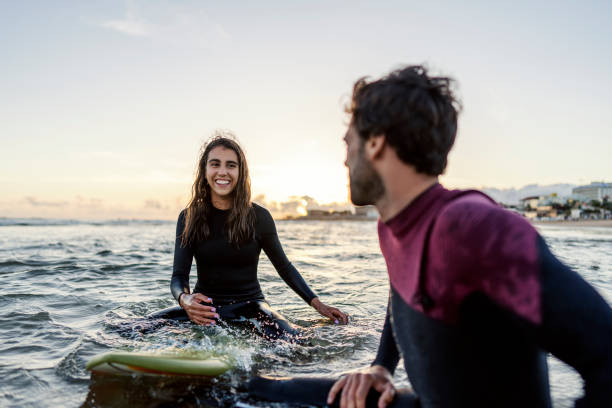 istock Happy people sitting on the surfboards in water and having fun. 2045432516