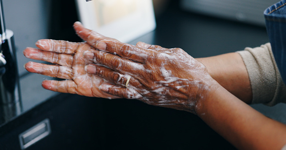 Person, soap and washing hands for hygiene, germ or bacteria removal by tap or sink at home. Closeup of palm in skincare, protection or soapy skin for cleaning, dirt or disinfection by basin at house