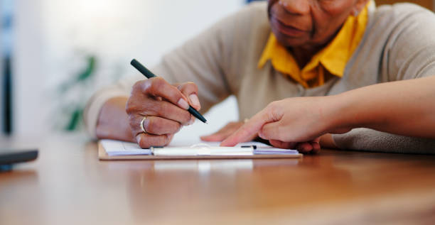 istock Senior woman, hands and writing on contract, form or application for retirement plan or insurance at home. Closeup of elderly female person signing documents, paperwork or agreement on table at house 2045437256