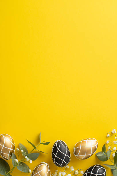istock Easter elegance captured. Overhead vertical image of exquisite black and gold eggs, fresh eucalyptus foliage, subtle gypsophila flowers, presented on vibrant yellow background, offering space for text 2045456307