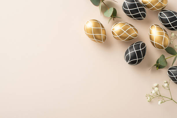 istock Grand Easter composition: top view shot of exquisite black and gold eggs, eucalyptus leaves, gypsophila, over a light beige ground, placeholder for script 2045456596