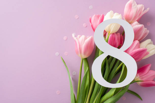 istock Celebrating Women's Day: A top view capturing the figure 8 amidst a vibrant array of tulips, dotted with confetti, on a gentle purple canvas, leaving space for messages 2045456606