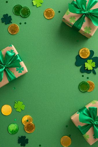 St. Patrick's day vertical magical display from top view, with shamrocks, gold coins, festooned boxes, and confetti, arranged on a green tableau, with space for copy