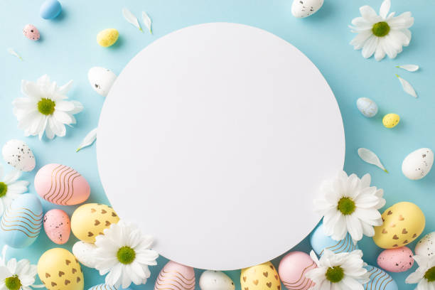 istock Easter mood setup: Flat-lay top view photograph of vibrant eggs, and spring daisies on a gentle blue backdrop, with an open circle for festive greetings or advertisements 2045457166