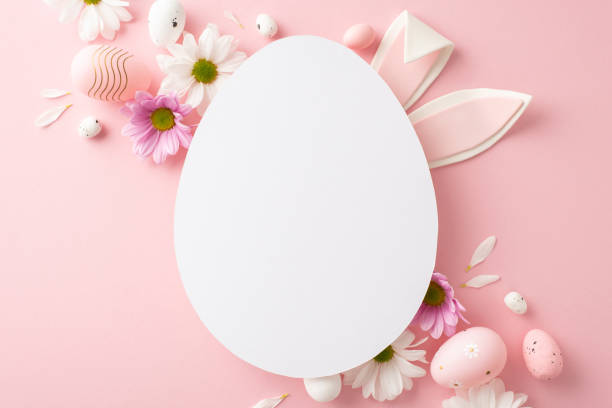 istock Easter elegance theme: Flat lay top view of tender eggs and chamomile flowers on pastel pink background, featuring sweet rabbit ears peeking from blank egg-shaped frame for personalized notes or ads 2045457185