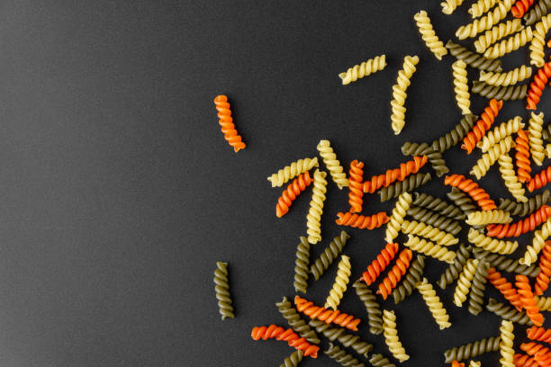 Raw pasta torti on black background.