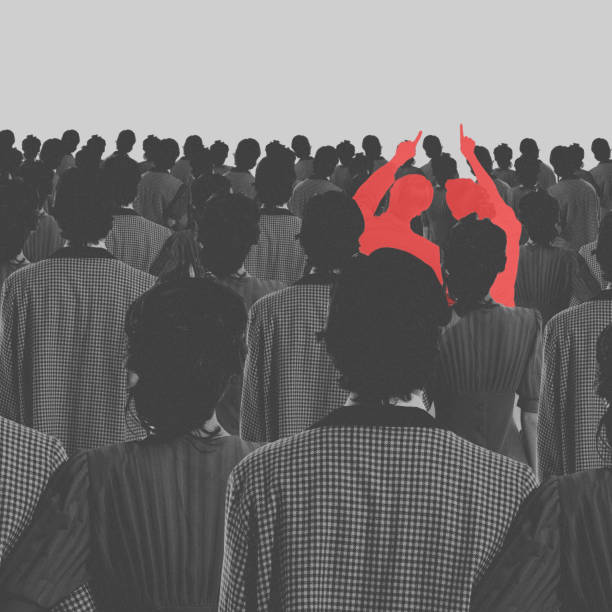 istock Two silhouetted individuals in red raising hands among monochrome crowd. Conceptual design. Power of individuality in a collective society. 2045478008