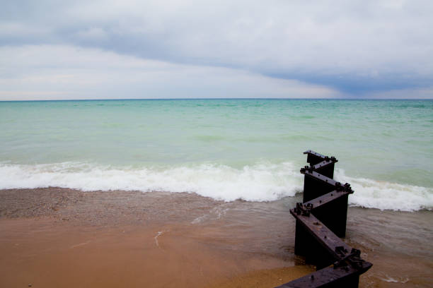 Tranquil beach scene on Lake Michigan with weathered metal remnants contrasting against natural elements, creating a serene and moody atmosphere.