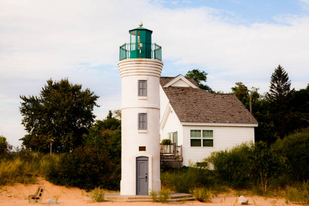Serene coastal living with a charming white lighthouse and house nestled in a secluded, natural setting. Capturing the tranquility and nautical heritage of Empire, Michigan.