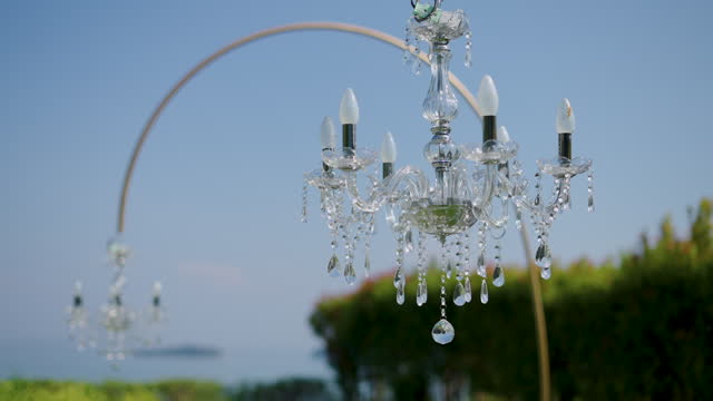 Chandelier hangs on ceiling set up wedding dinner party.