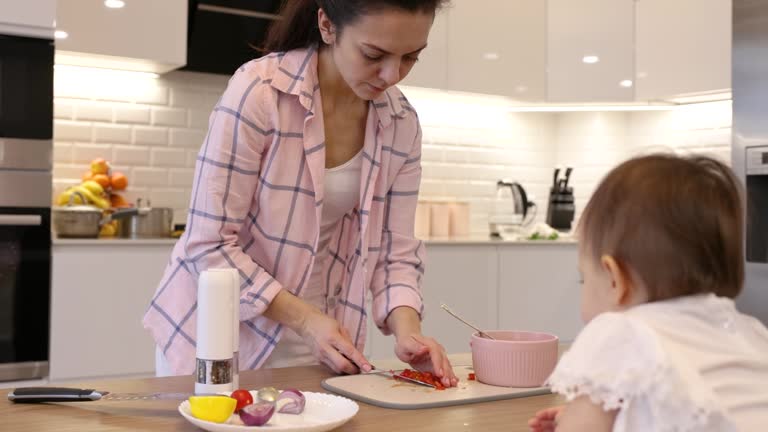 female hands cutting tomatoes on cutting board with kitchen knife