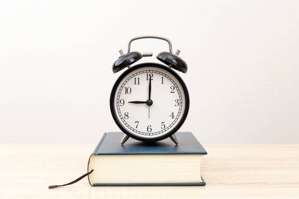 istock A thick book and a clock on the desk. 2045523400