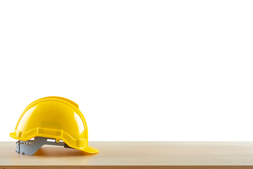 Yellow safety construction helmet on wood table isolated on white background