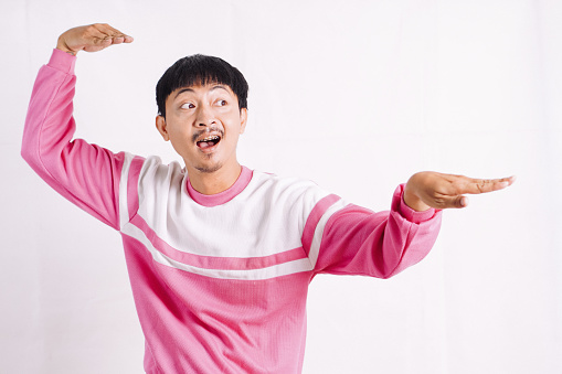 funny young man with raised arms in kung fu pose while looking at camera
