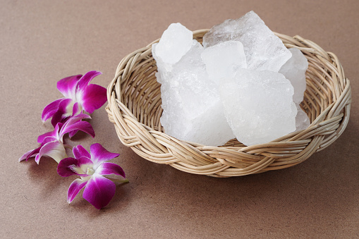 Crystal clear alum stones or Potassium alum on basket, decorated with flowers. Useful for beauty and spa treatment. Use to treat body odor under the armpits as deodorant and make water clear.