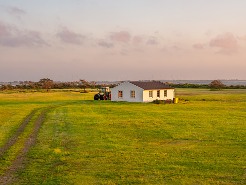 Pasture with barn and tractor in polder at golden hour on East Frisian island Langeoog, Lower Saxony, Germany