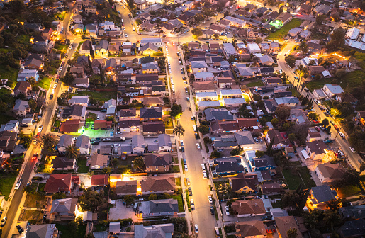 An aerial view of homes in Los Angeles, illuminated at dusk by street lighting.
