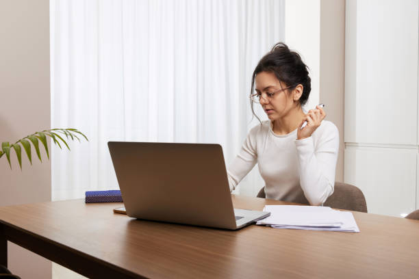 istock pretty woman in glasses using laptop at home 2045594142