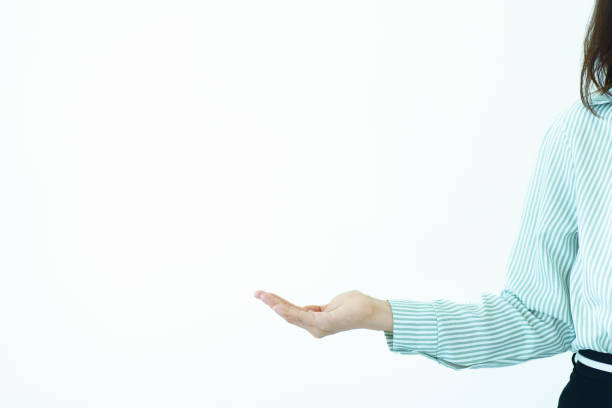 Asian businesswoman in business smart casual wardrobe standing on the white background showing her hand in the empty space. Smart and good looking businesswoman showing a hand.