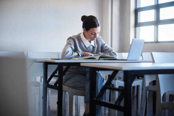 istock Young female college student doing homework alone in a classroom at school 2045632979