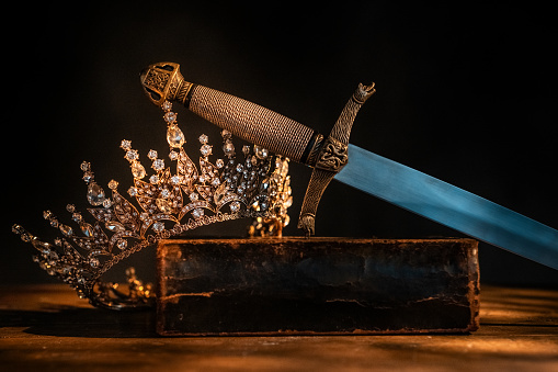 Holy Bible, crown and dagger on wooden background