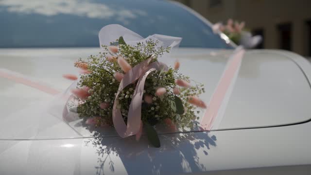 Close-up shot of a wedding bouquet and ribbons on the front of a wedding car