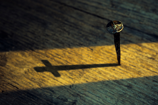 A wood cross on an old church steeple backlighted by a rising sun. Some copy space.