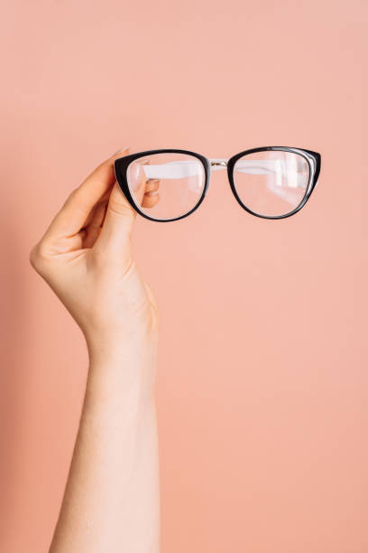istock Vision glasses with black frames in a woman's hand against a pink background 2045654180