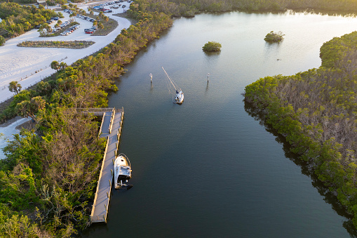 Capsized sunken sailing boat left forsaken on shallow bay waters after hurricane Ian in Manasota, Florida.