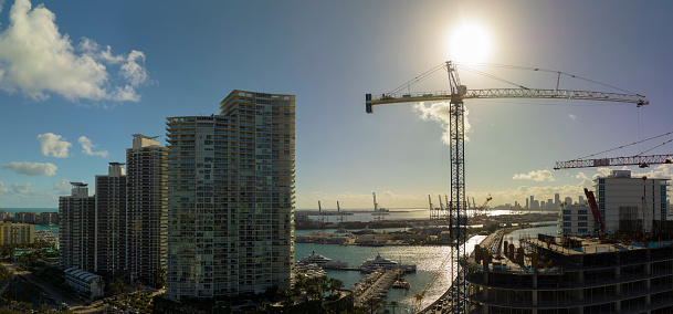 Aerial view of new developing residence in American urban area. Tower cranes at industrial construction site in Miami, Florida. Concept of housing growth in the USA.