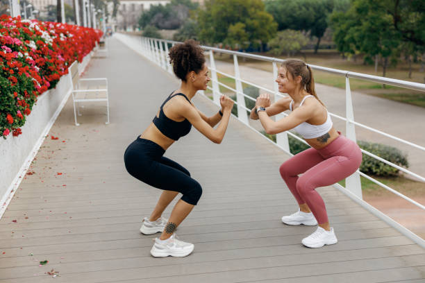 istock Two smiling fit women doing workout and squatting together outdoors. Active lifestyle concept 2045672773