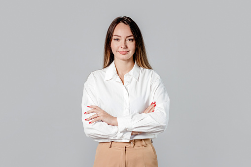 caucasian business lady in white shirt with folded hands at office desk isolated on gray background
