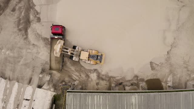 4K overhead view of a mechanical digger loading a tipper truck in a very wet quarry