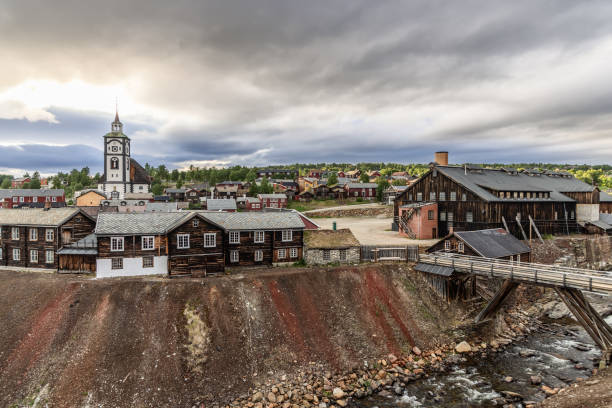 Golden light bathes the historical Roros with its prominent church and Smeltehytta, capturing the town's rich mining legacy against a dramatic sky Golden light bathes the historical Roros with its prominent church and Smeltehytta, capturing the town's rich mining legacy against a dramatic sky roros mining city stock pictures, royalty-free photos & images