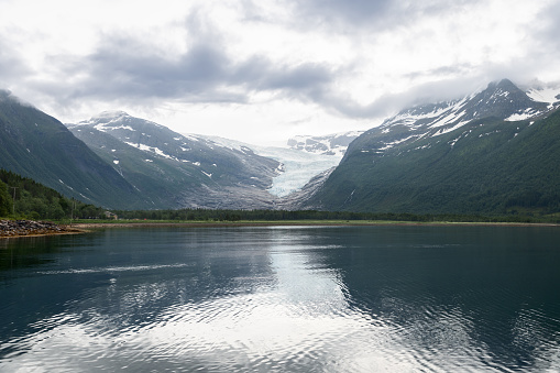 Svartisen Glacier's grandeur is mirrored in the still waters of the fjord, a serene reflection of Norway's dynamic landscape and glacial beauty