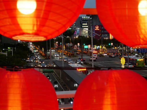 The traditional lanterns for the Chinese Lantern Festival are colorful and adorned with various patterns. With the vehicles coming and going on the busy main road, illuminated by the streetlights.