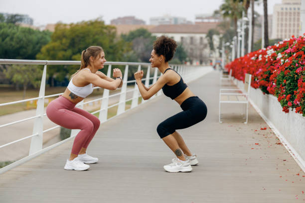 istock Two active young women doing workout and squatting together outdoors in the city 2045698125