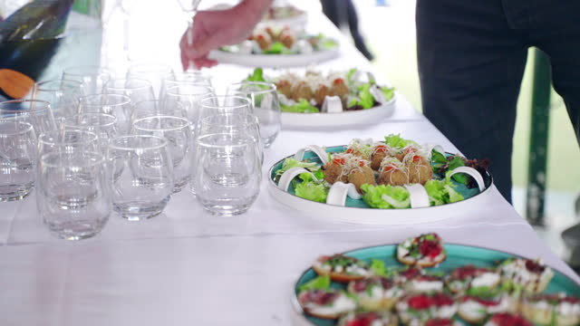 Luxury catering service table on exit celebration party, food trays and crystal glasses for invited guests, assortment of appetisers, snacks and canapes on plates
