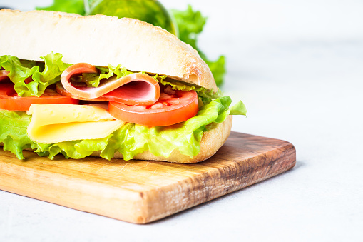Ciabatta sandwich with lettuce, cheese, tomatoes and ham. Healthy fast food snack. Isolated on white.