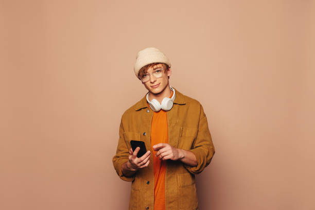 istock Happy young man using smartphone on vibrant peach background 2045754401