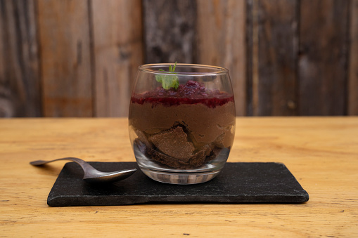 Sweet desserts. Closeup view of a chocolate pudding with red berries puree, served in a glass.
