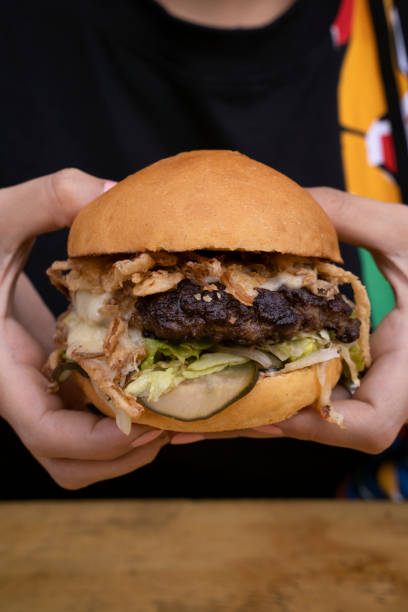 istock A woman holding a giant burger 2045768396