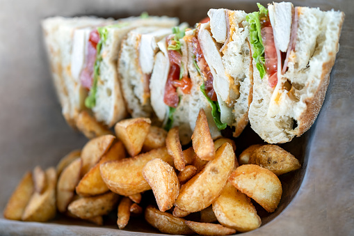 a club sandwich and fried potato on a wooden plate