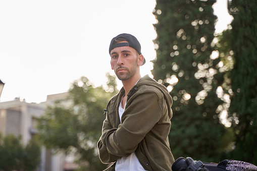 young man looking at the camera wearing a cap and urban clothes