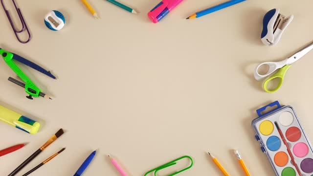 Colorful school stationery appear on pastel beige background.