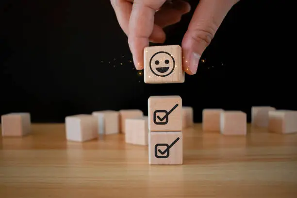 Photo of Emoticon face Customer service evaluation concept Hold up a cube with a checkbox on Excellent Smile Face Rating for a Satisfaction Survey. emoticon face in cube shape. checklist in cube shape.