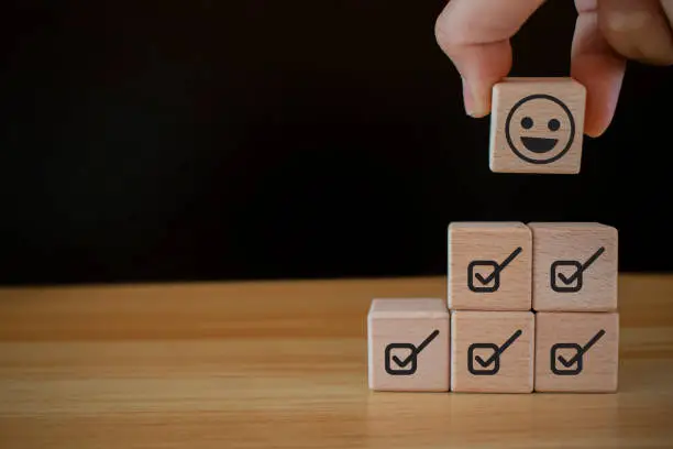 Photo of Emoticon face Customer service evaluation concept Hold up a cube with a checkbox on Excellent Smile Face Rating for a Satisfaction Survey. emoticon face in cube shape. checklist in cube shape.