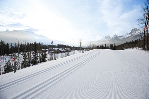 An overall view of the ski tracks, stadium area and day lodge at the Canmore Nordic Centre Provincial Park in Alberta, Canada. It was the site of the 1988 Winter Olympics and numerous international competitions since. The tracks on the left are set for the classic-style technique, and the tracks on the right are for the skating-style technique. Visible in the photo are the Three Sisters mountain peaks.