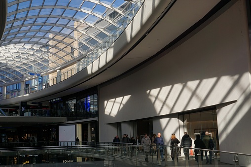 Edinburgh, Scotland - 26 February 2024: Sunshine is flooding through the glass roof in the St James Centre Shopping Mall creating shadows in an upper level.